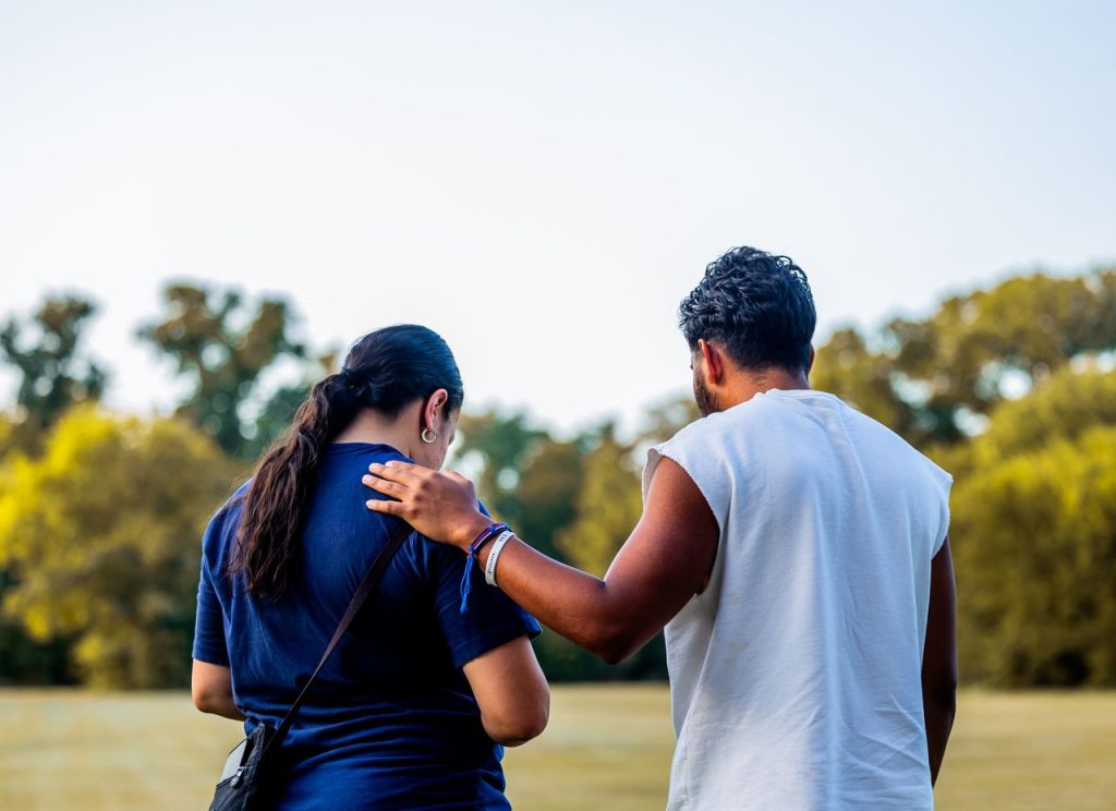 Two friends walking together in a park, showcasing friendship, support, and togetherness.